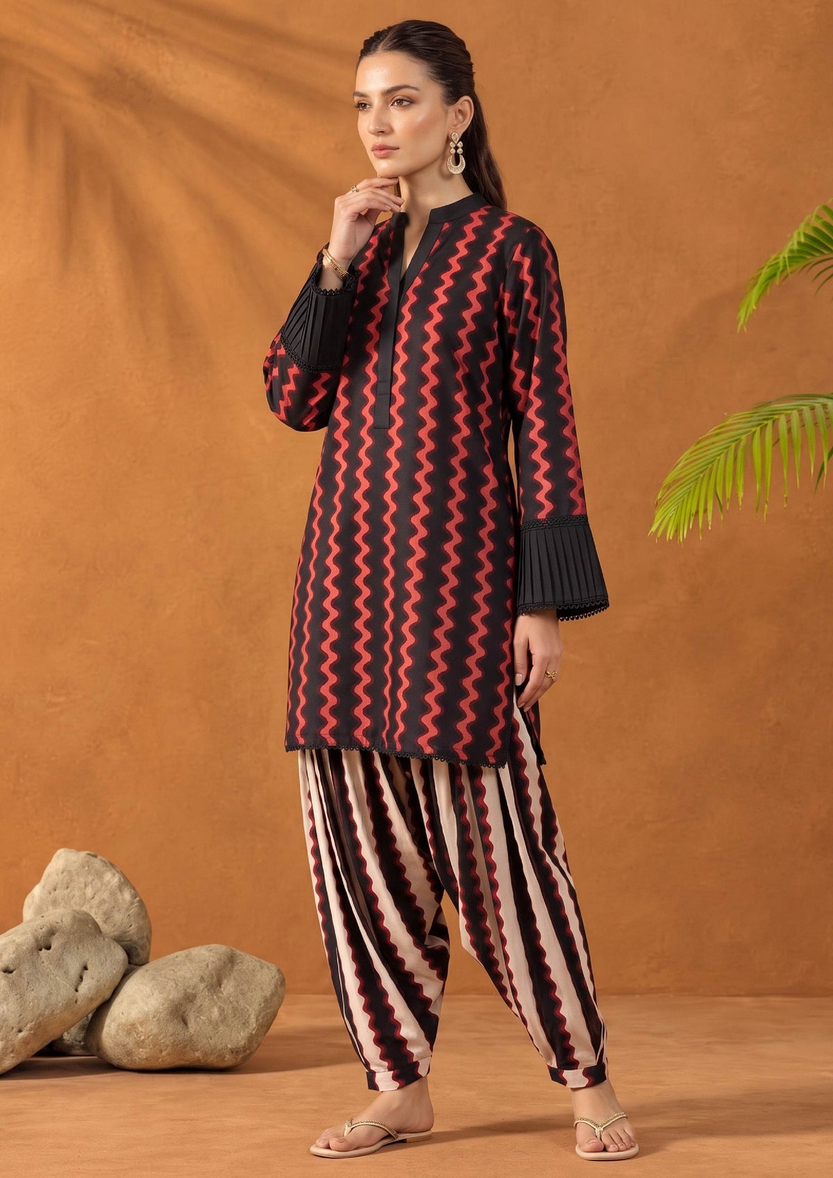 Model wearing Crimson Ripple black and red printed lawn suit with pleated cuff shirt and striped shalwar by Mirasl