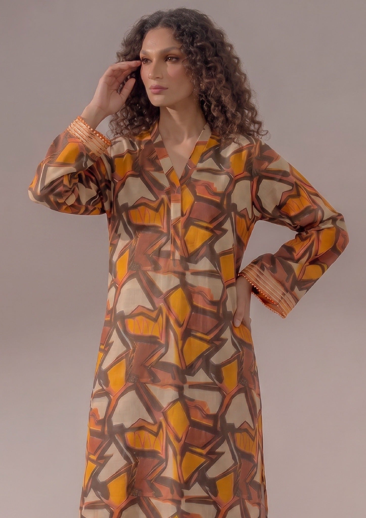Seated model wearing Retro Rust 2 piece printed lawn co-ord set by Mirasl with abstract printed shirt, wide trouser, and summer ready styling.