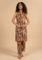 Seated model wearing Linear Illusion 2 piece printed lawn co-ord set by Mirasl with sleeveless printed shirt, straight trouser, and summer ready styling.