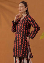 Seated model wearing Crimson Ripple by Mirasl, a black and crimson red printed lawn co-ord set with ripple print shirt, coordinated stripe trouser, lace finishing, and summer ready styling.