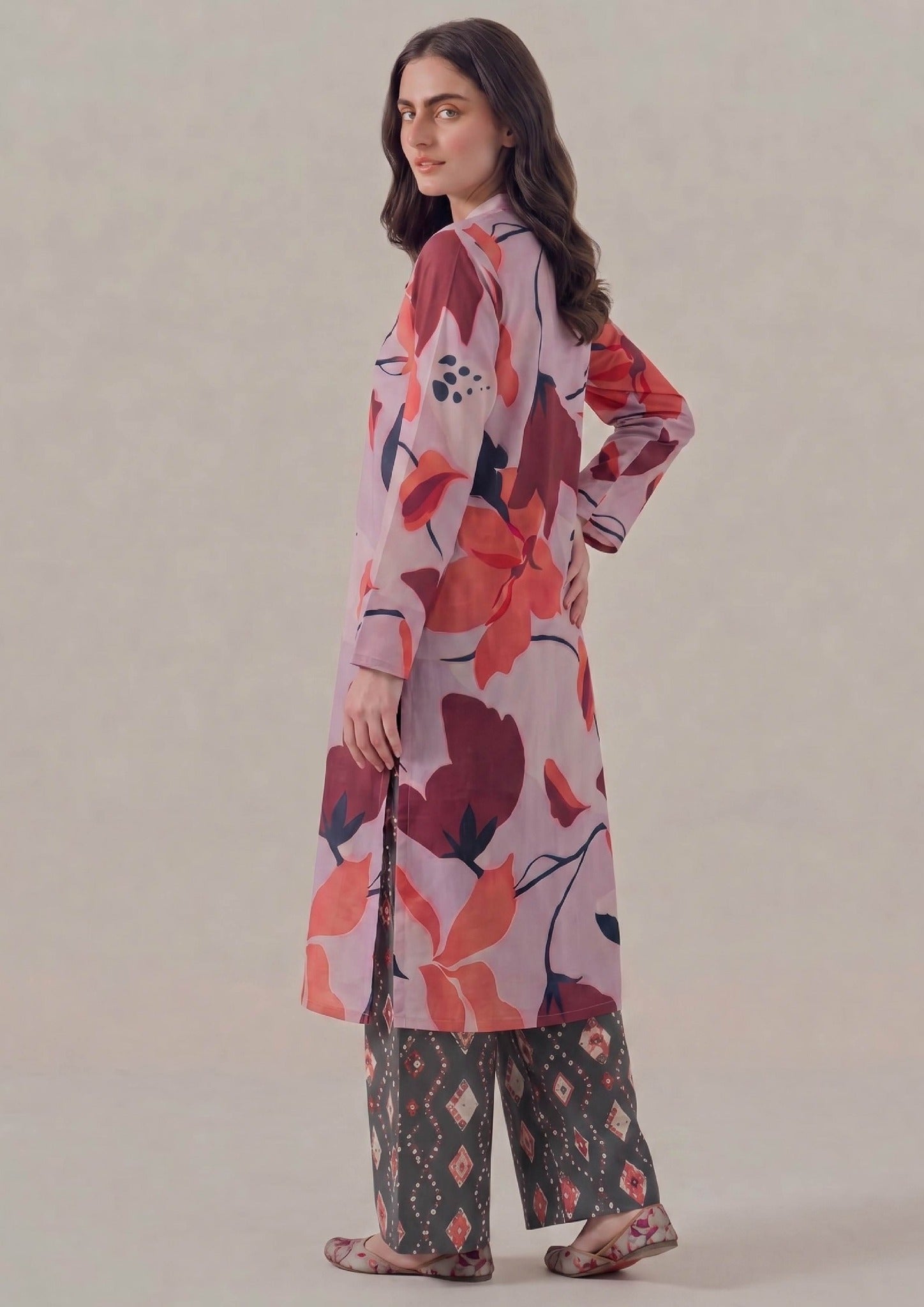 Side view of Crimson Ikat printed lawn co-ord set featuring lilac pink floral shirt, crimson and coral leaf motifs, side slits, charcoal ikat printed trouser, and easy summer styling.