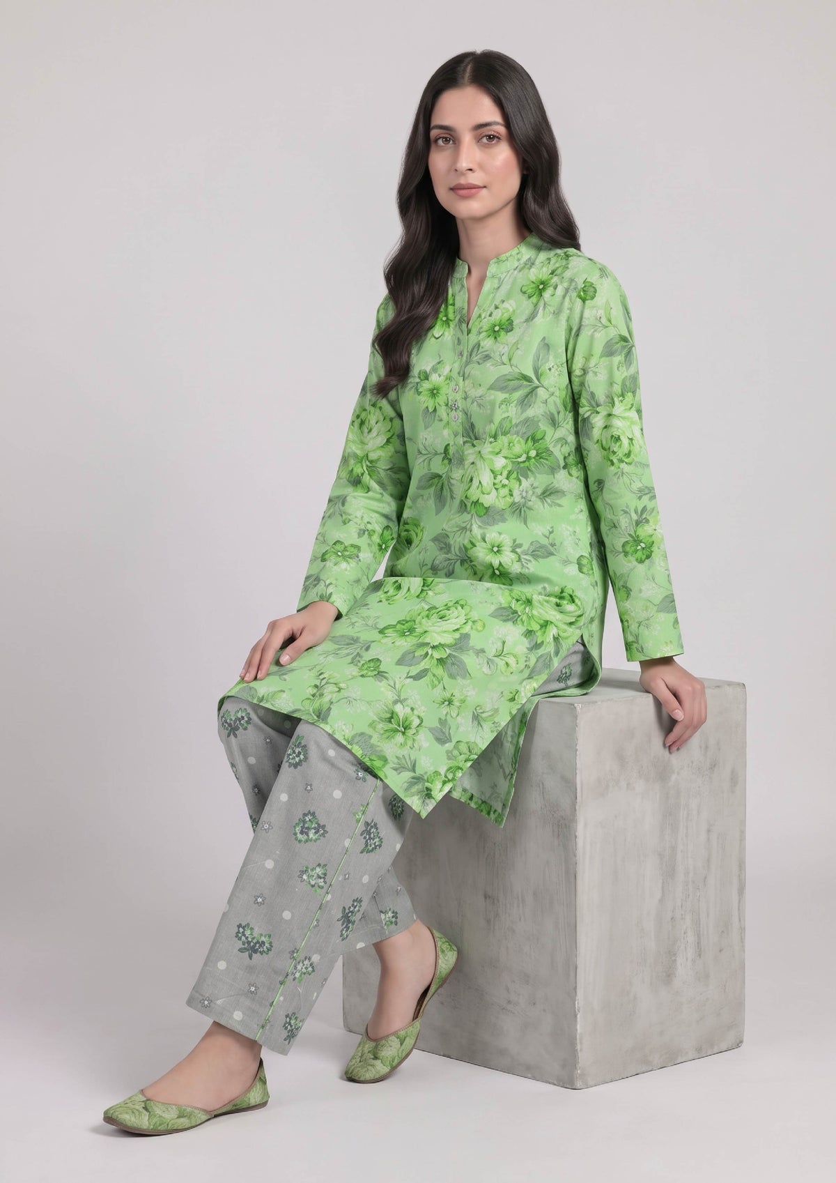 Seated view of Mint Meadow Pakistani lawn suit featuring a mint floral shirt and grey printed wide-leg trousers