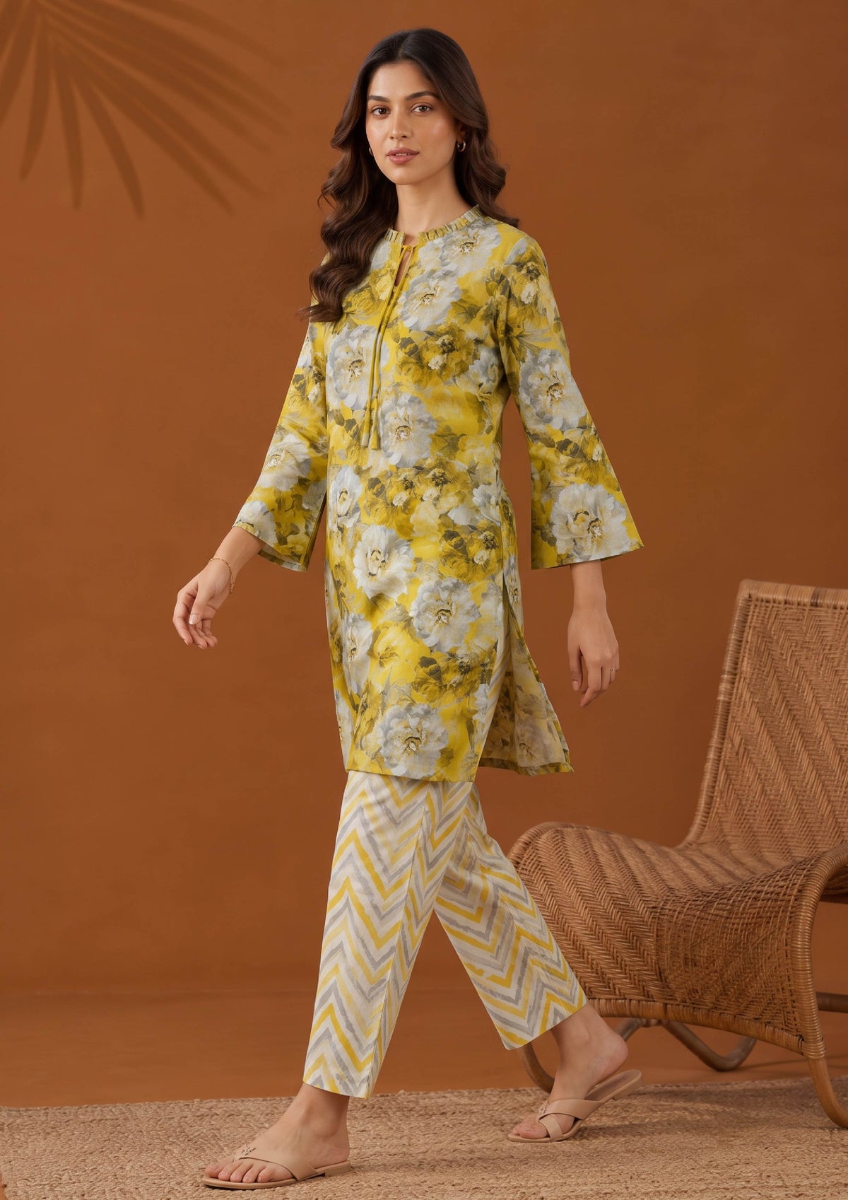 Walking view of Solenne lawn co-ord set with yellow floral shirt and cream chevron printed trousers by Mirasl