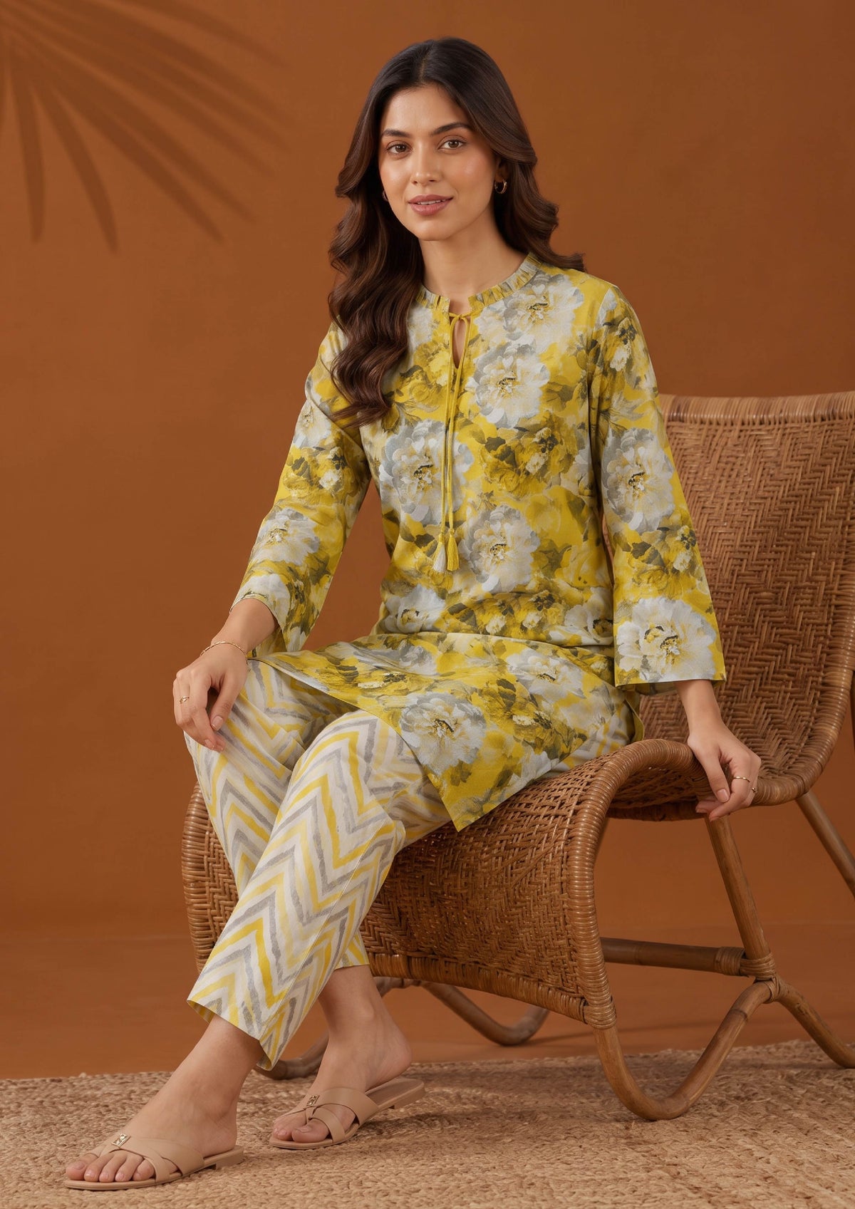 Seated view of Solenne Pakistani lawn suit featuring a mustard floral shirt and coordinated printed trousers