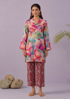 Model wearing Mirasl Blossom Bramble 2 piece co-ord set with multi-color floral printed lawn knee-level shirt and rust red printed straight trouser.
