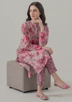 Seated model wearing Mirasl Blossom Fusion stitched lawn 2 piece co-ord set with floral printed shirt and geometric printed trouser.