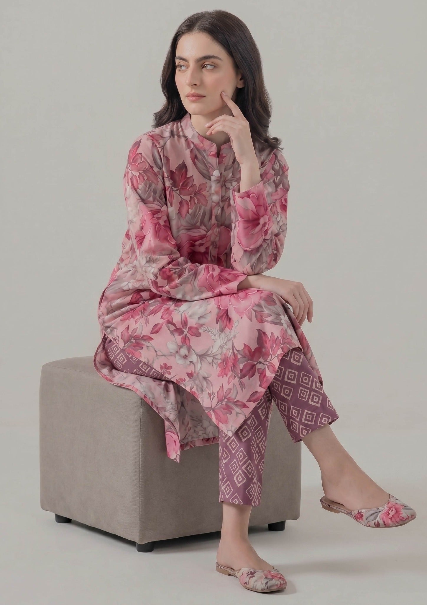 Seated model wearing Mirasl Blossom Fusion stitched lawn 2 piece co-ord set with floral printed shirt and geometric printed trouser.