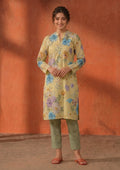 Model wearing Mirasl Cerulean Flora 2 piece co-ord set with pale yellow floral printed lawn knee-level shirt and sage printed straight trouser.