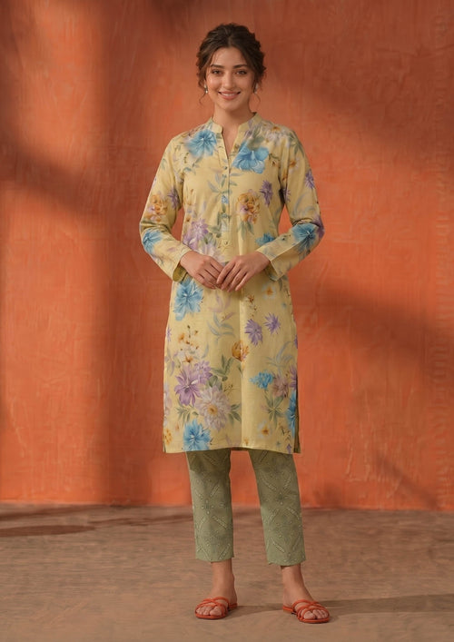 Model wearing Mirasl Cerulean Flora 2 piece co-ord set with pale yellow floral printed lawn knee-level shirt and sage printed straight trouser.