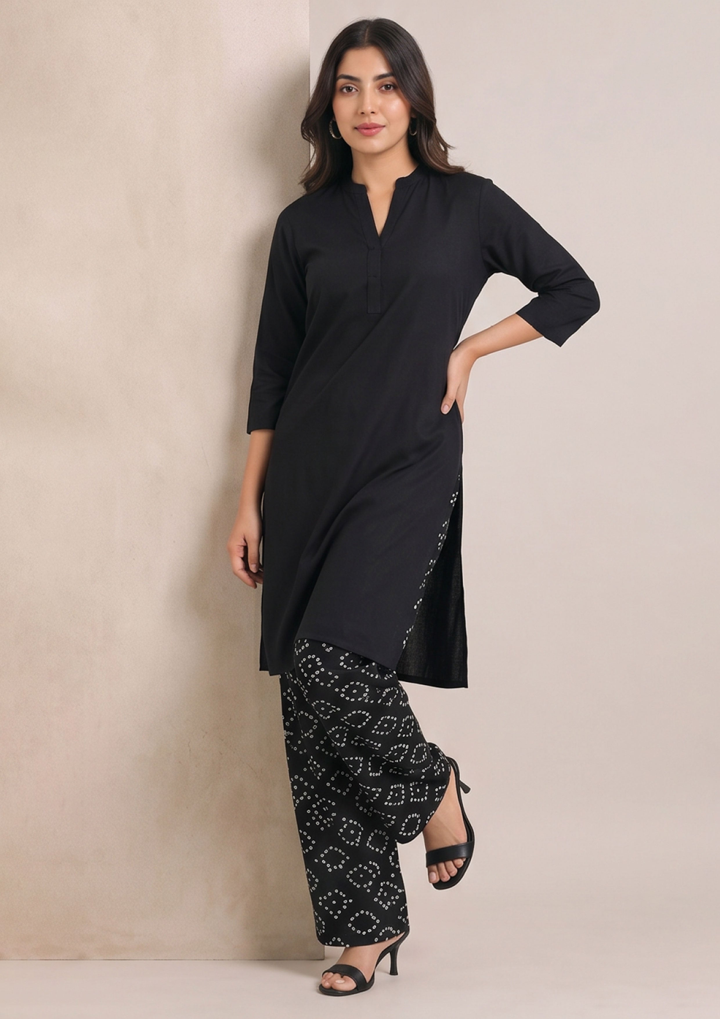 Walking front view of Chunri Lounge Noir 2 piece ready to wear suit with solid black kurta and relaxed white chunri printed trouser
