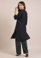 Seated view of Chunri Lounge Noir women co-ord set showing minimalist black shirt and wide-leg chunri printed trousers