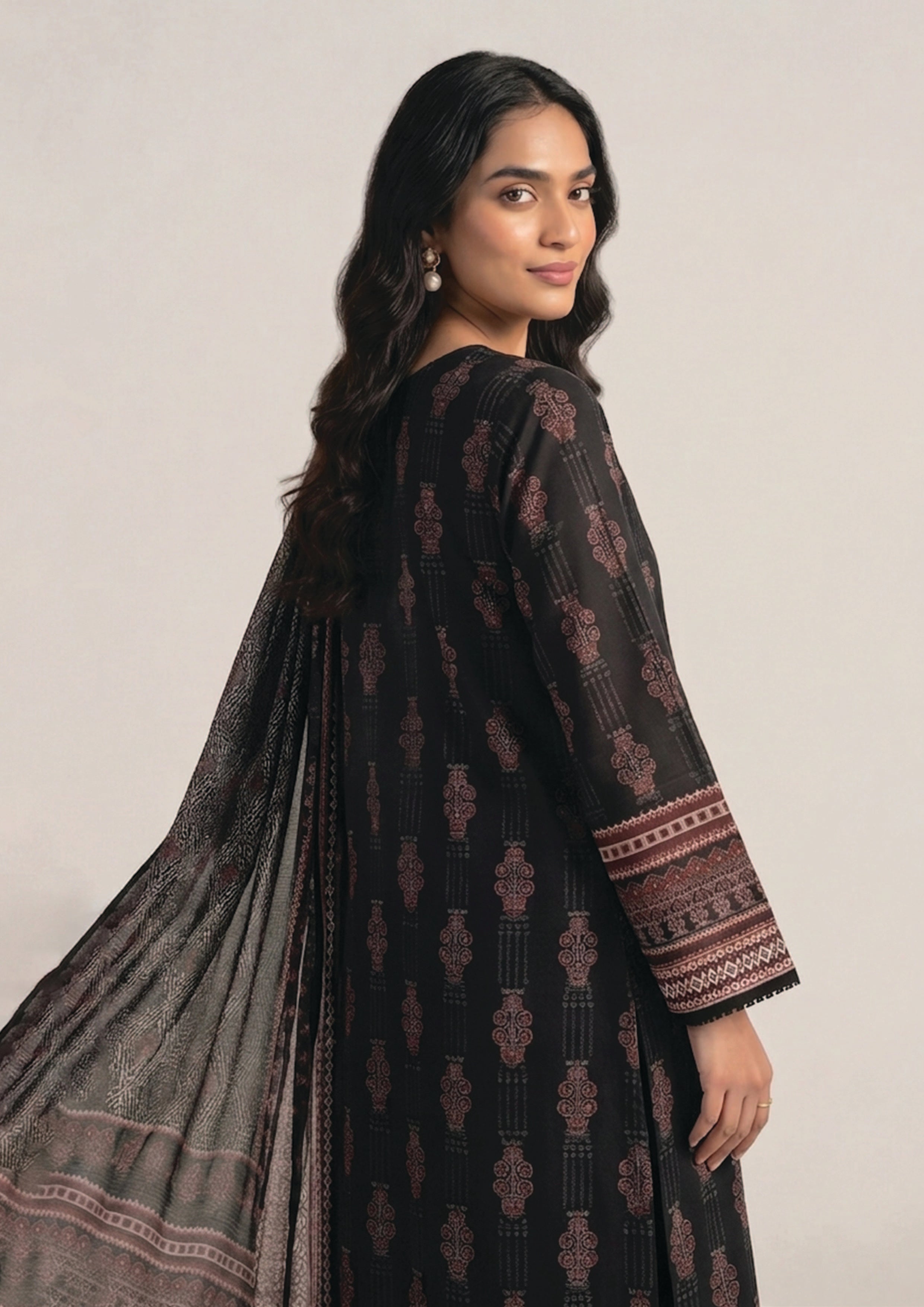 Side view of Crimson Mosaic Noir black Pakistani lawn suit showing flowing printed dupatta and geometric border