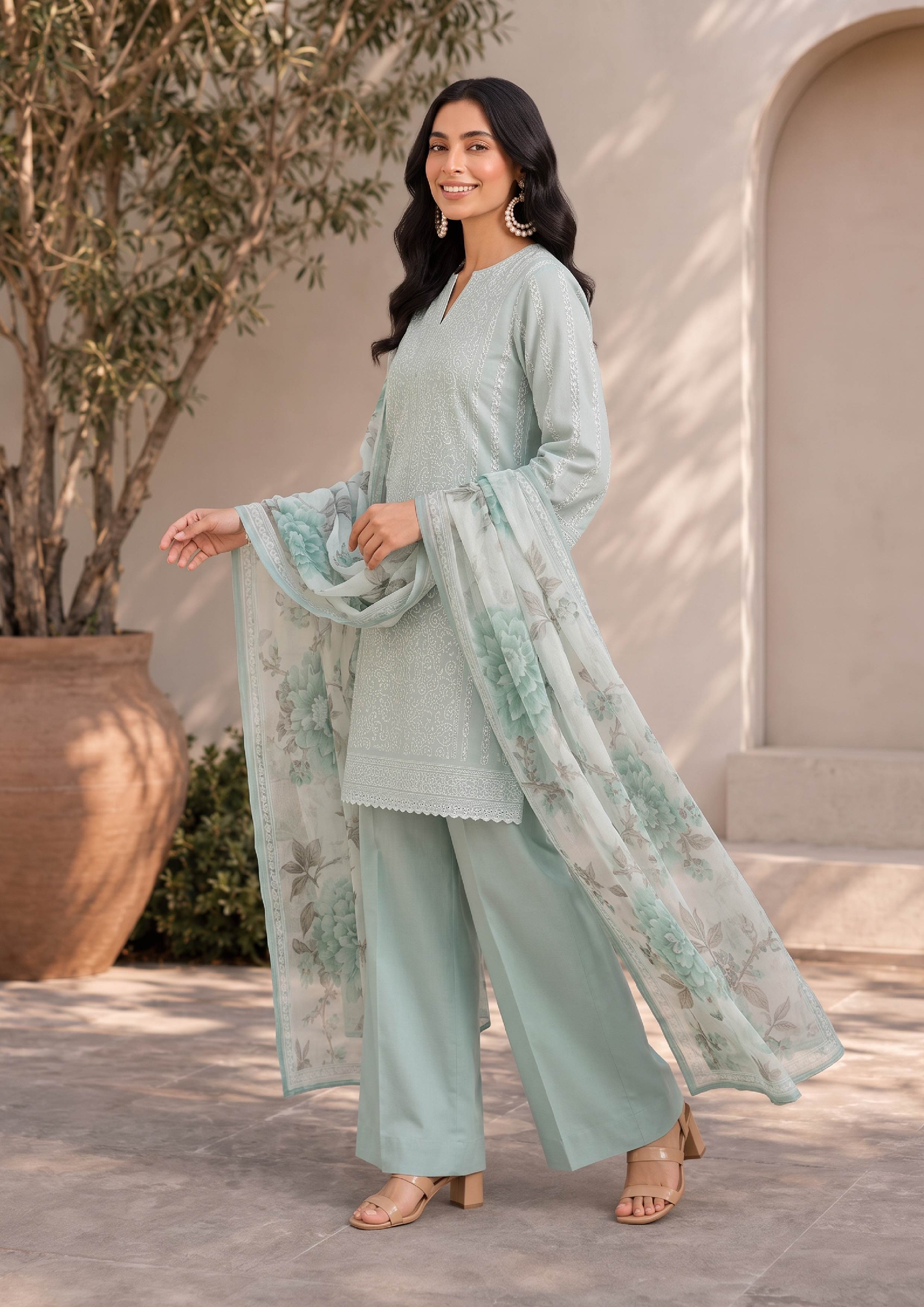 Side smiling pose of a mint green embroidered lawn suit paired with a white floral printed chiffon dupatta and mint green palazzo trousers, showcasing elegant Pakistani fashion – fasl-e-rang – mirasl