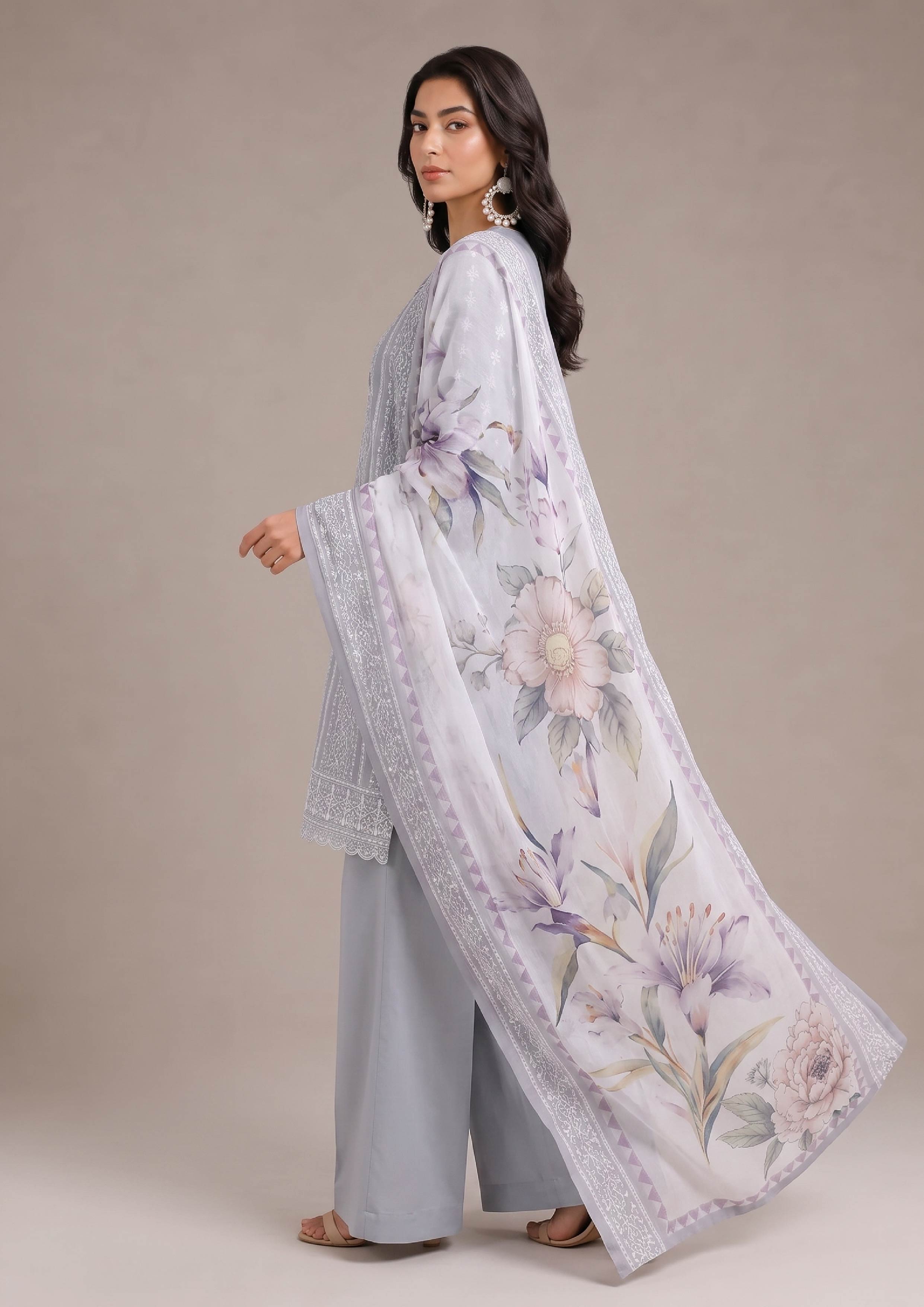 Pakistani embroidered lawn suit in pearl grey featuring mist grey trousers and a flowing soft lilac floral dupatta shown in a stylish side profile from the fasl-e-rang collection by mirasl.