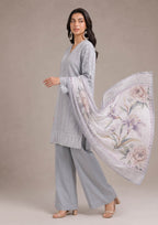 Premium embroidered lawn suit in pearl grey and mist grey with a soft lilac floral printed dupatta in a walking pose, showcasing elegant summer wear from the fasl-e-rang collection by mirasl.
