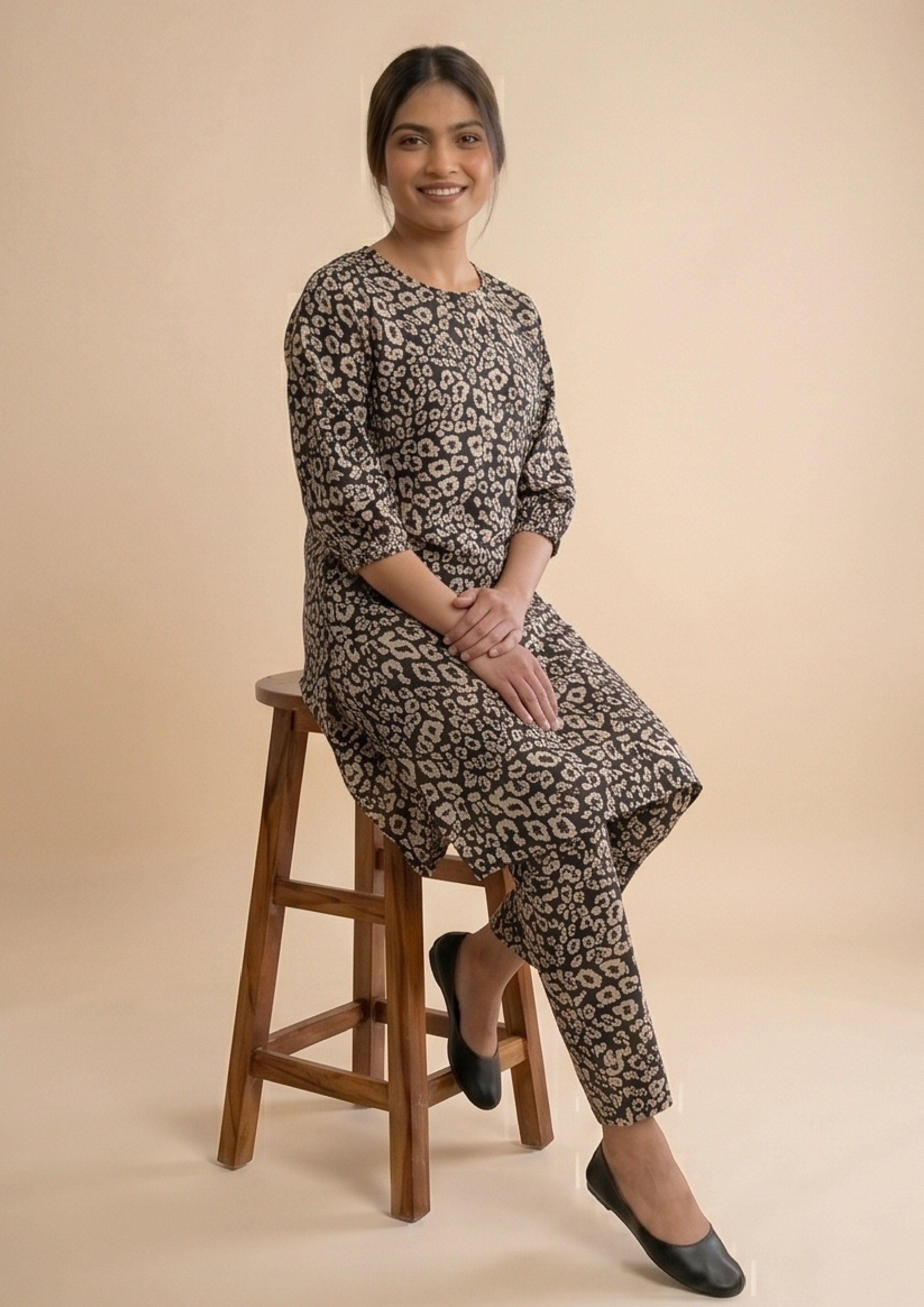 Seated view of Golden Print Co-ord black lawn coard suit with sandy gold print and matching straight trousers