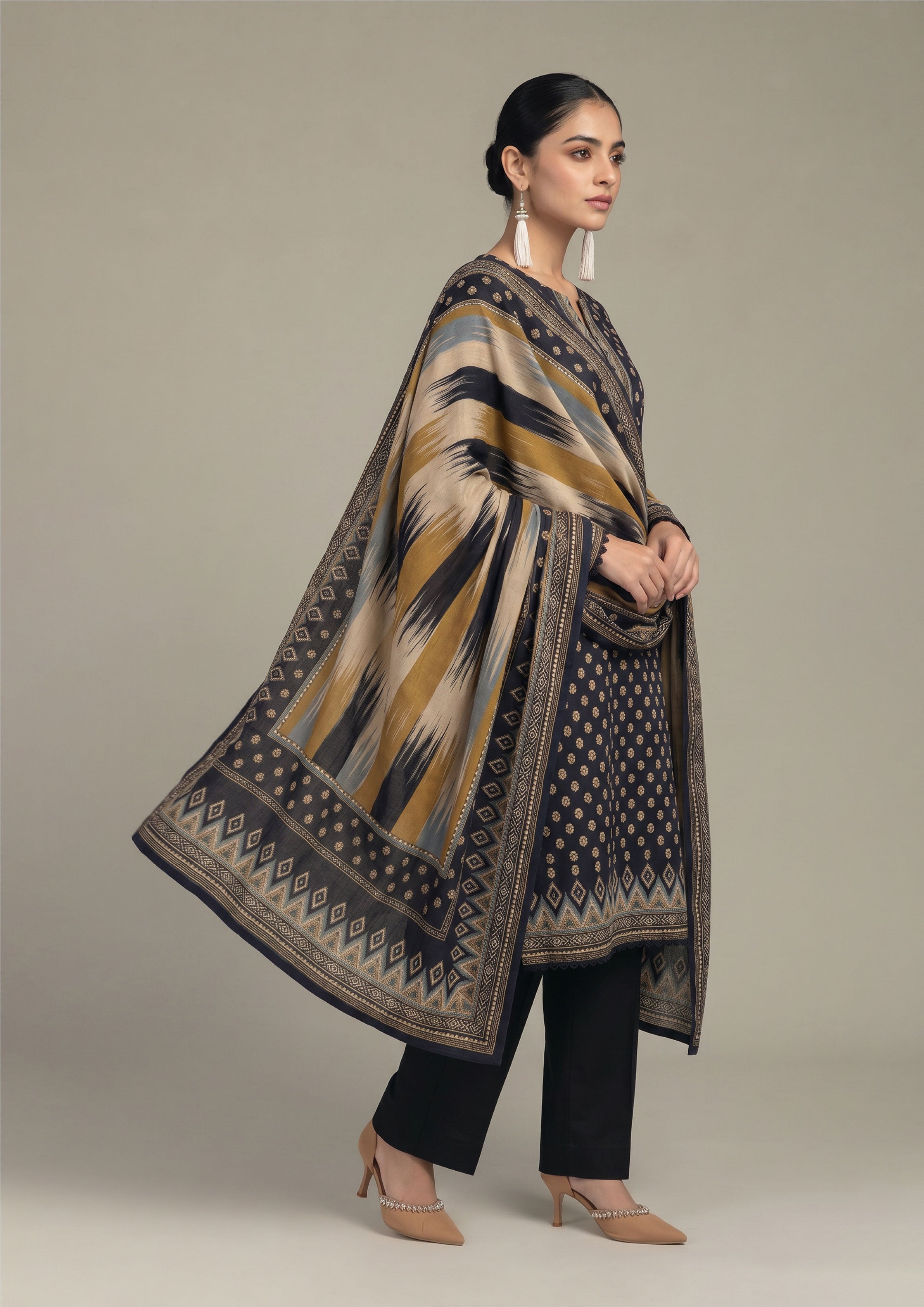 Seated model wearing Ikat Fusion Noir women stitched lawn suit with artistic ikat dupatta, navy printed kurta and black trouser