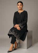Side walking view of Minimalist Noir 2 piece ready to wear suit with scalloped embroidered hem, flared side panel and black trouser