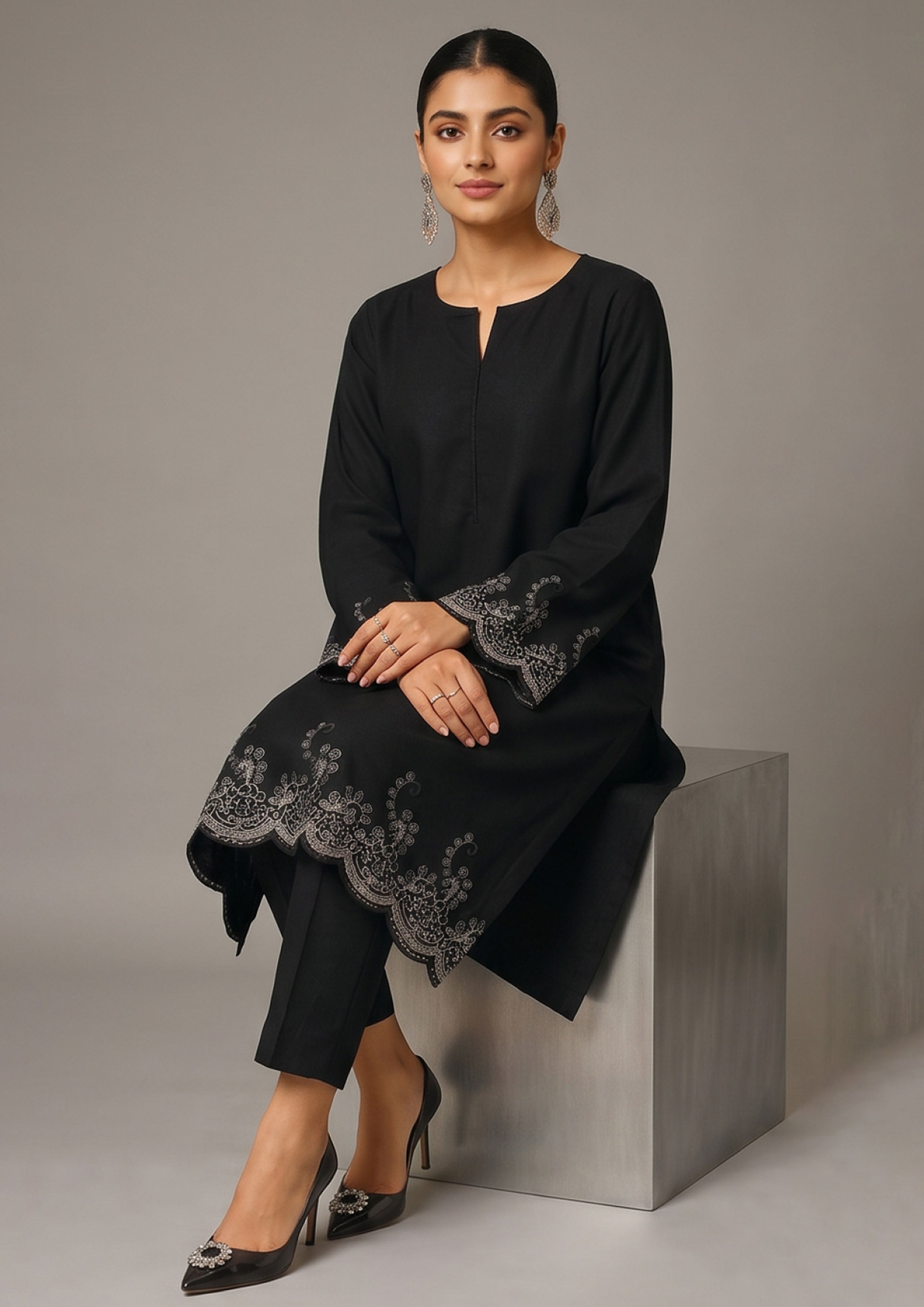 Side walking view of Minimalist Noir 2 piece ready to wear suit with scalloped embroidered hem, flared side panel and black trouser