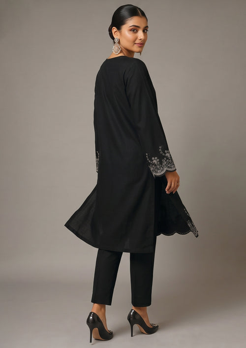 Front view of Minimalist Noir black coard suit for women with long embroidered shirt, scalloped hem and slim black trouser