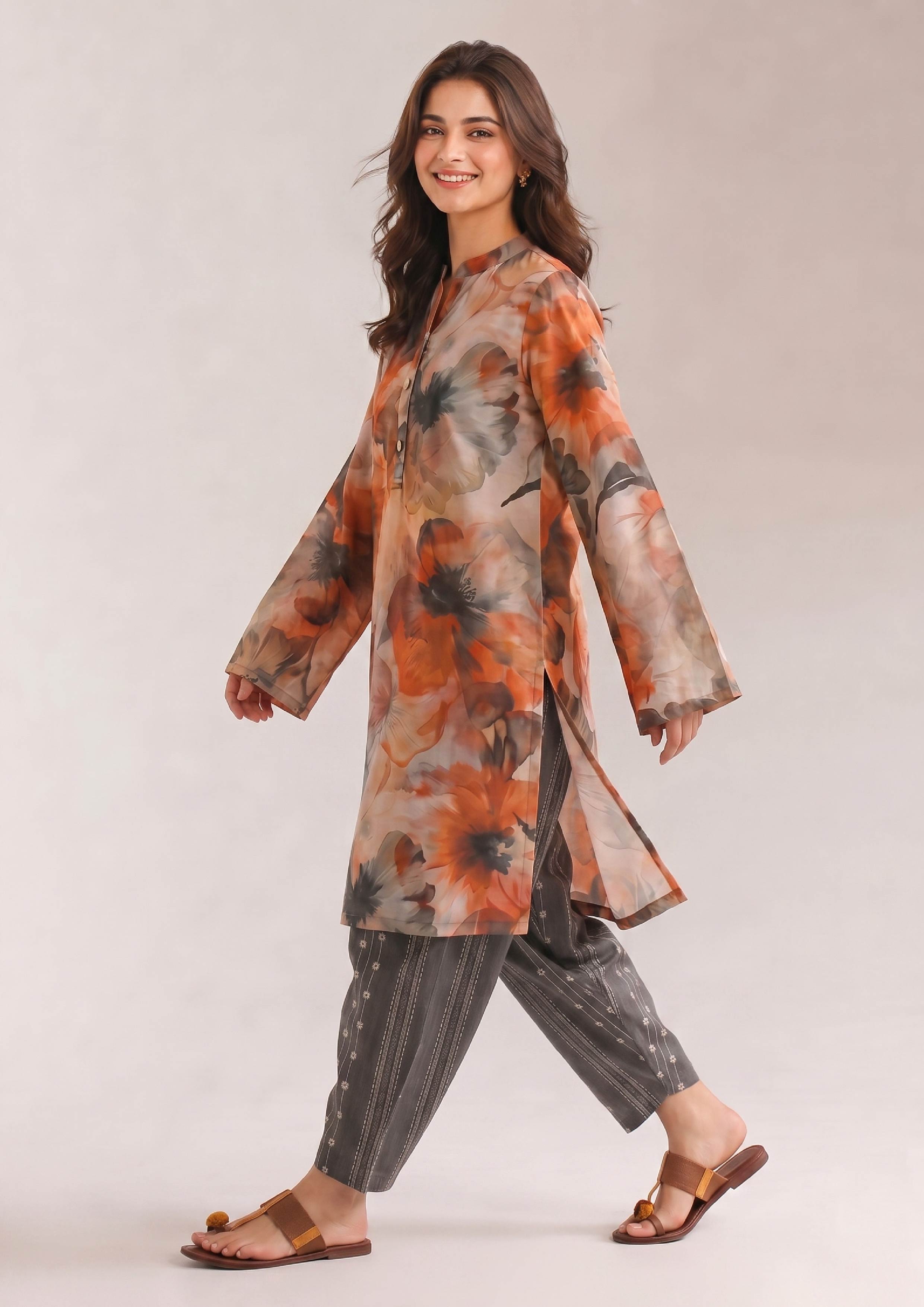 Lifestyle walking pose of a women's orange, beige and charcoal grey floral Printed Lawn Suit with striped trousers from the Fasl-e-Rang collection by Mirasl.