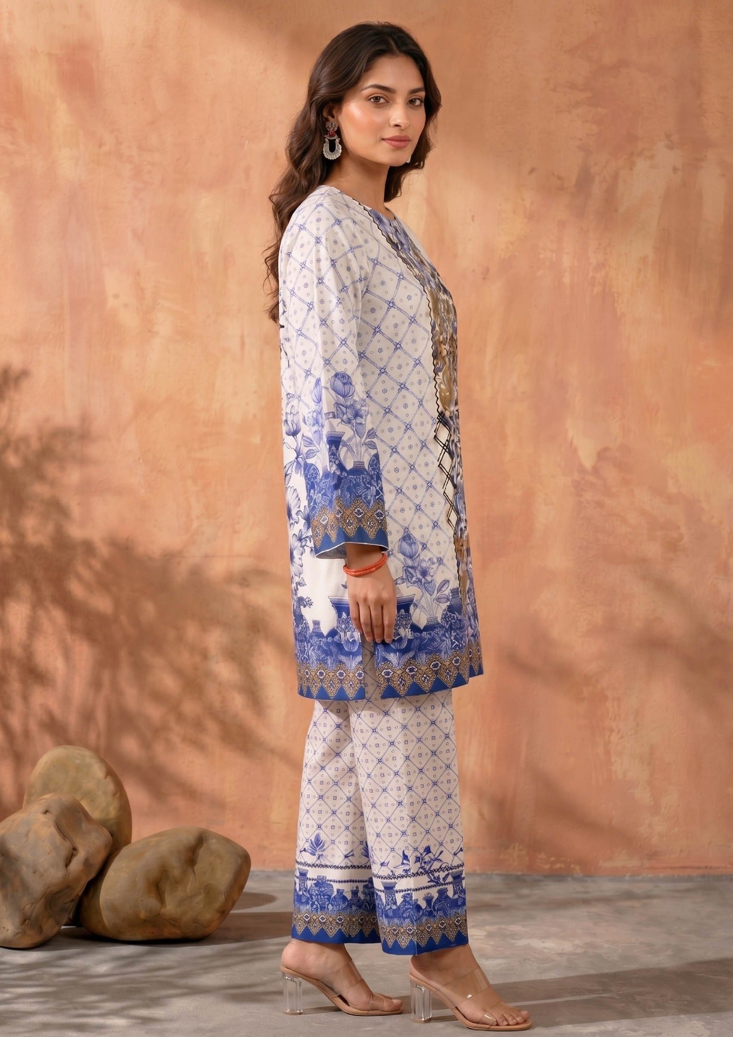 Seated model wearing Mirasl Ornate Ocean printed lawn co-ord set with ornate blue floral shirt, border sleeves, and matching printed straight trouser.