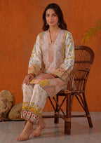 Seated model wearing Mirasl Peach Blossom 2 piece printed lawn co-ord set with soft peach floral shirt and printed straight trouser.