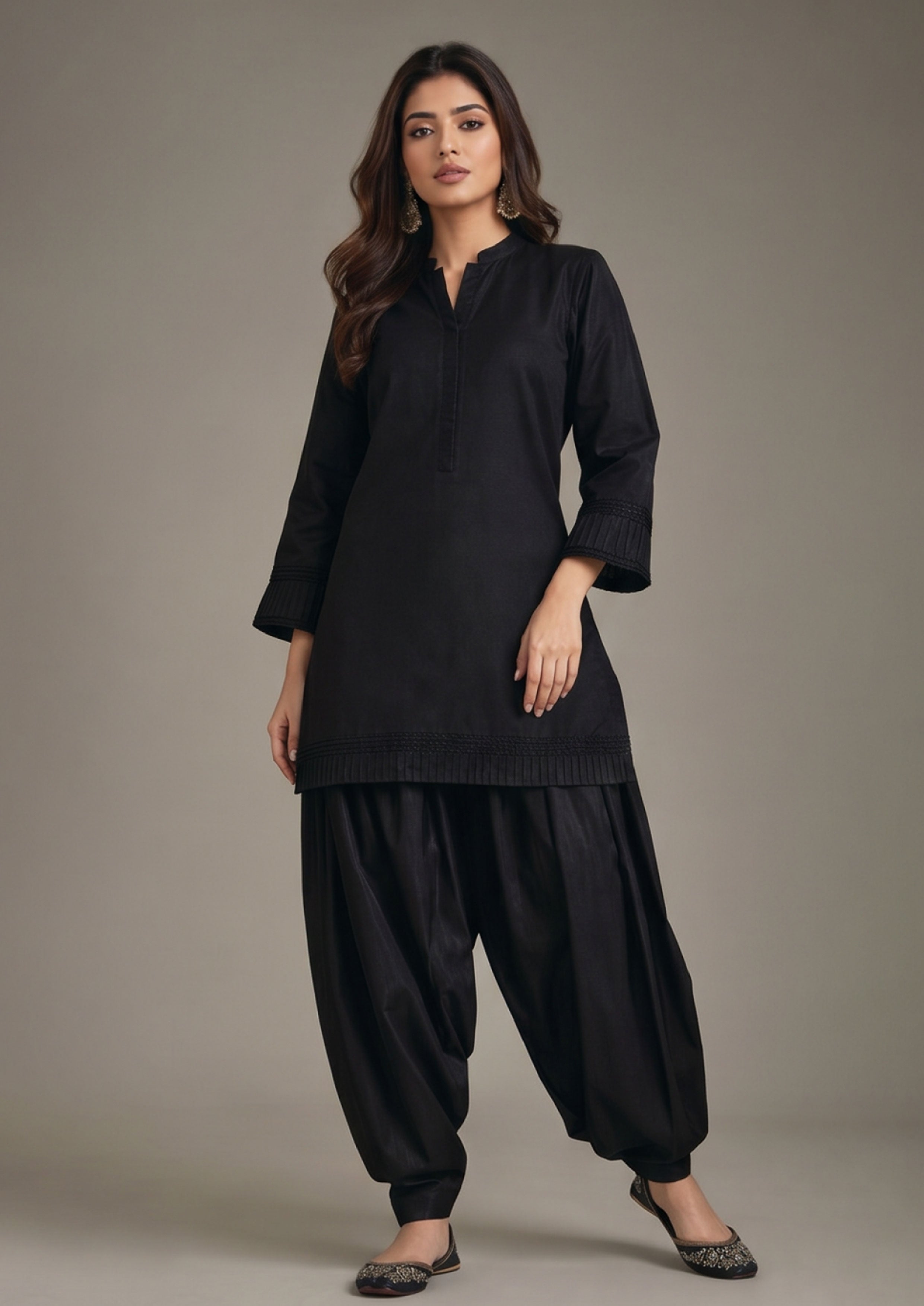 Front standing view of Pleated Afghani Noir Afghani shalwar suit with black pleated shirt, band collar and relaxed draped shalwar