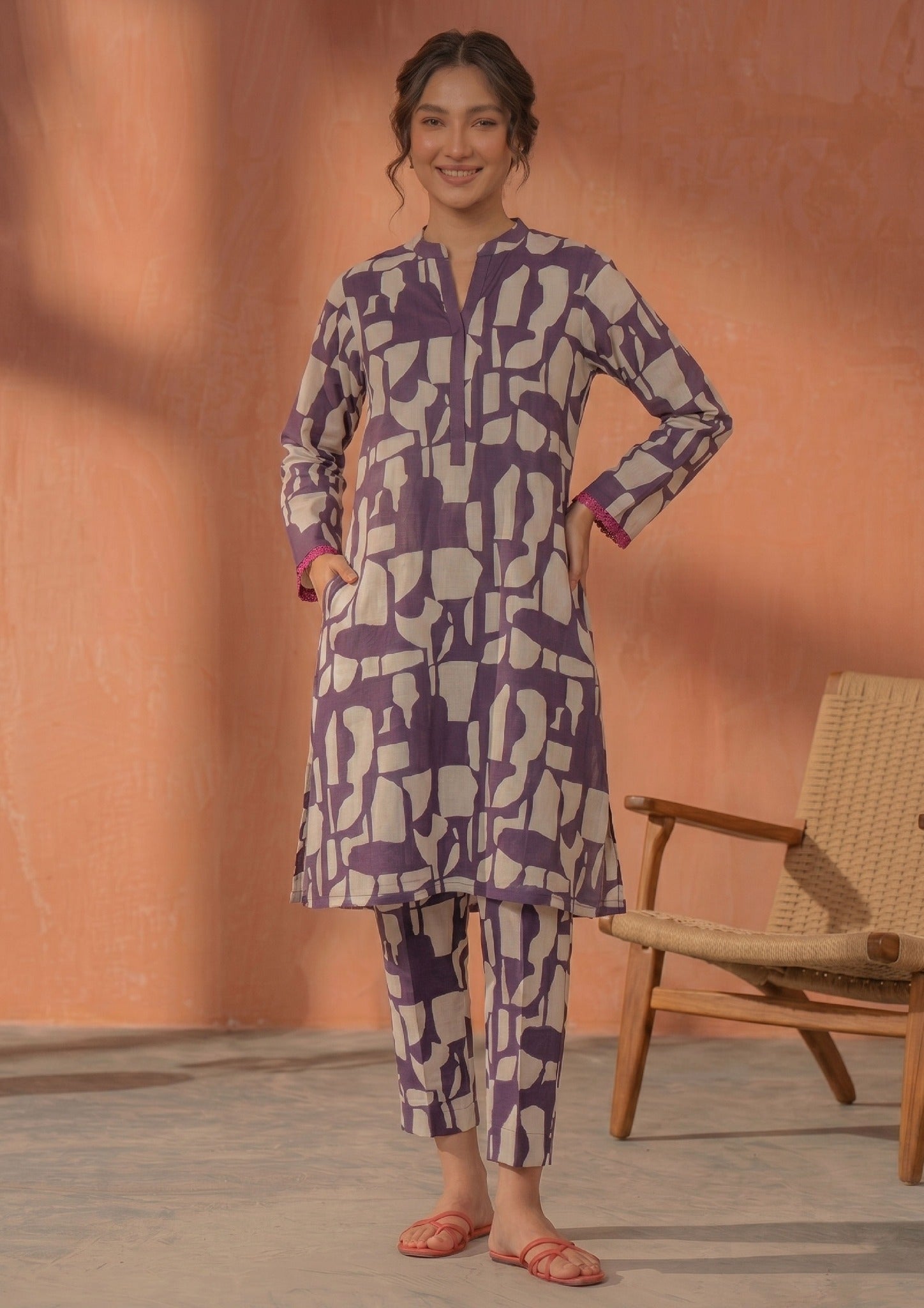 Seated model wearing Plum Mosaic 2 piece printed lawn co-ord set by Mirasl with abstract printed knee-level shirt, straight trouser, and summer ready styling.