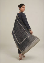 Seated model wearing Sage Chunri Noir Pakistani lawn suit with micro chunri print, sage borders and leheriya-style dupatta