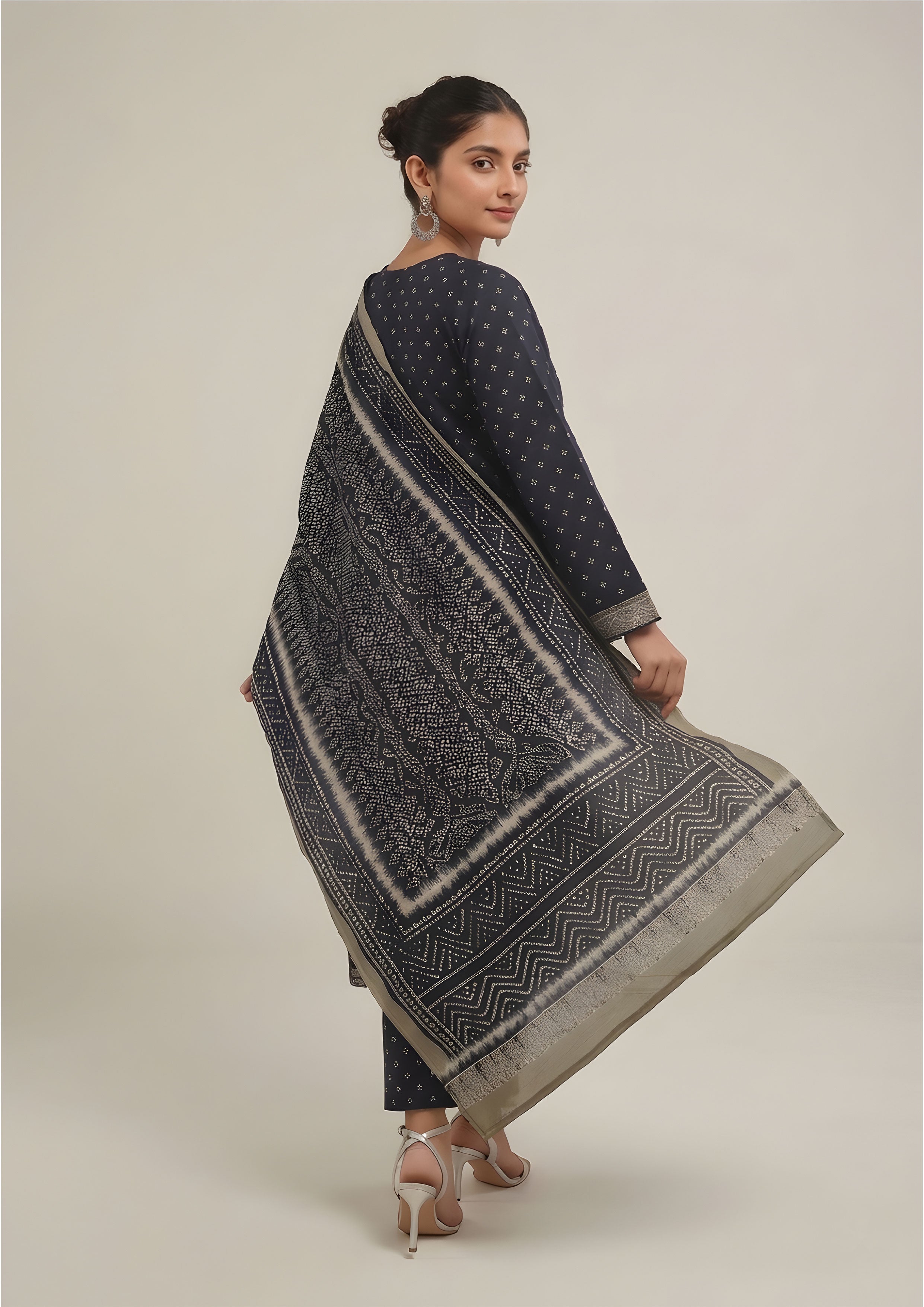 Seated model wearing Sage Chunri Noir Pakistani lawn suit with micro chunri print, sage borders and leheriya-style dupatta