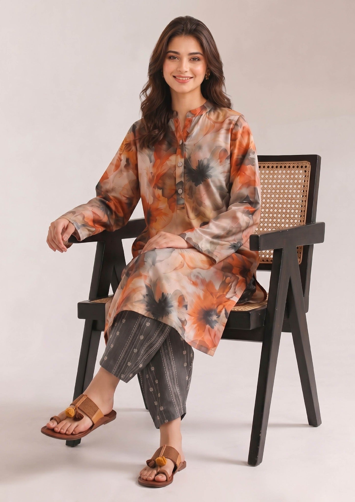 Seated view of Mirasl Sienna Sunset printed lawn co-ord set featuring warm floral artwork and coordinated grey printed trouser.